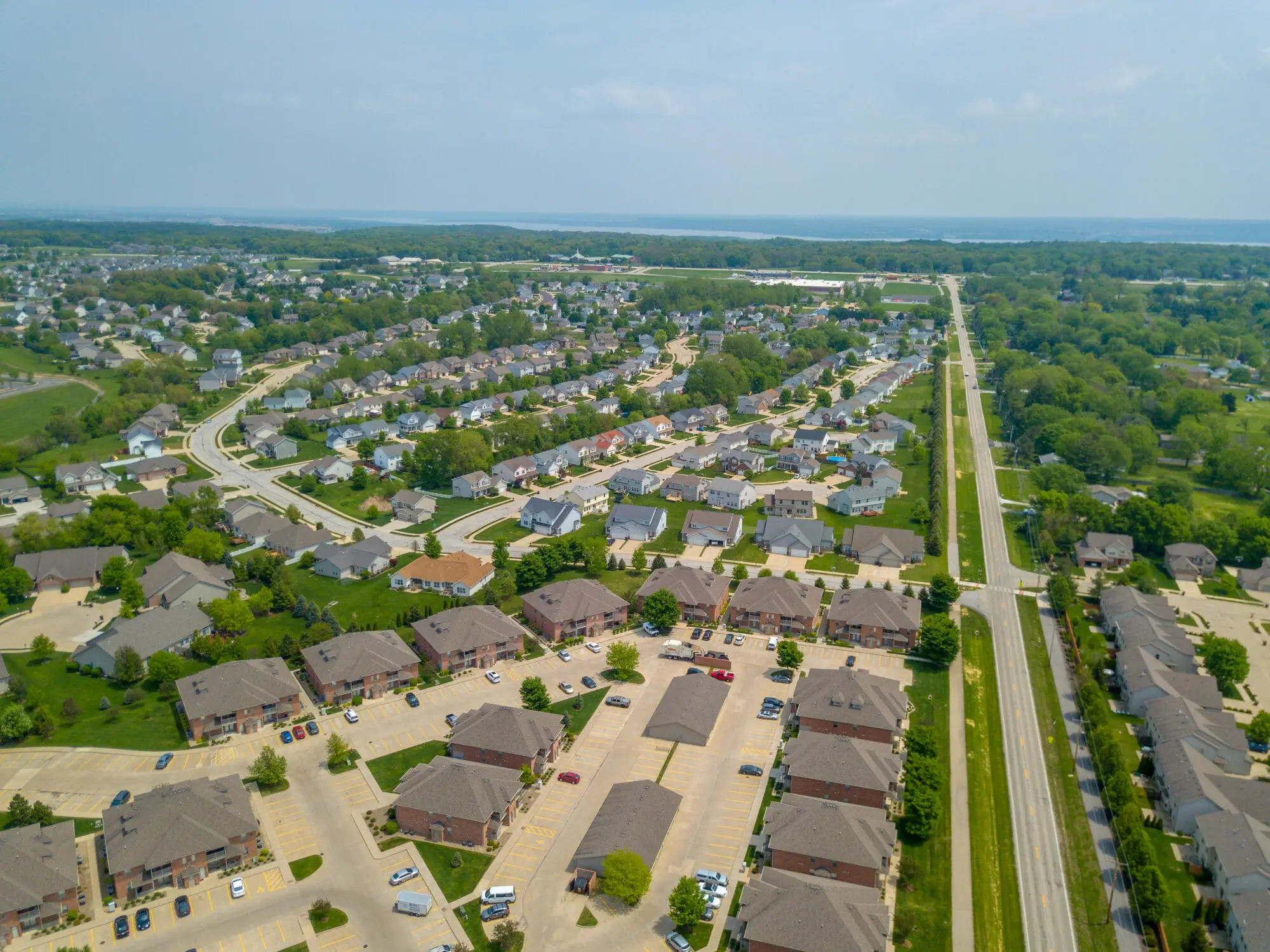 Aerial view of suburban neighborhood with houses, trees, and parking areas